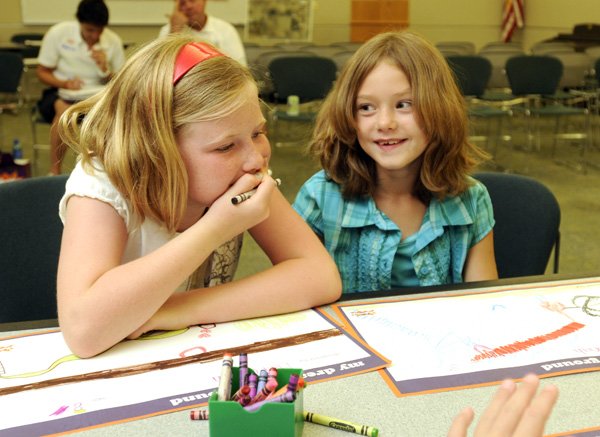 Meredith Laman, 8, left, and Savannah Peters, 8, laugh as they create their dream playground Tuesday at the Rogers Public Library. Several children gathered for the design day organized by KaBOOM to help design a playground at the library. The playground will be one of 10 built by the Dr Pepper Snapple group and KaBOOM in 2010.