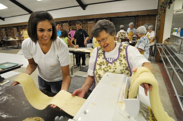 Kara Jo McKinley, left, and Jettie Franco roll pasta before it is cut into spaghetti and hung to dry on Thursday at St. Joseph Catholic Church parish hall. More than 40 volunteers worked to produce the first of four batches of spaghetti for dinners to be served Aug. 5-7 during the 112th Tontitown Grape Festival.