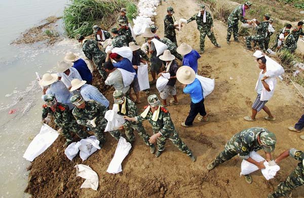 Workers and police officers fortify a dike with sandbags Tuesday in Pengze, China.