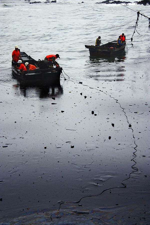  Chinese firefighters work Tuesday in the oily waters of the Yellow Sea off the coast of Dalian.