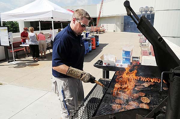 FILE - University of Arkansas employee Gabe Velasco grills up some hamburgers and hot dogs for University staff and faculty in front of the HPER Building during the faculty and staff appreciation picnic in Fayetteville. (Arkansas Democrat-Gazette/Michael Woods)
