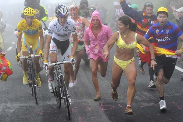 Spectators run alongside stage winner Andy Schleck of Luxembourg (right) and overall leader Alberto Contador of Spain (left) as they climb Tourmalet pass in dense fog during the 17th stage of the Tour de France on Thursday.