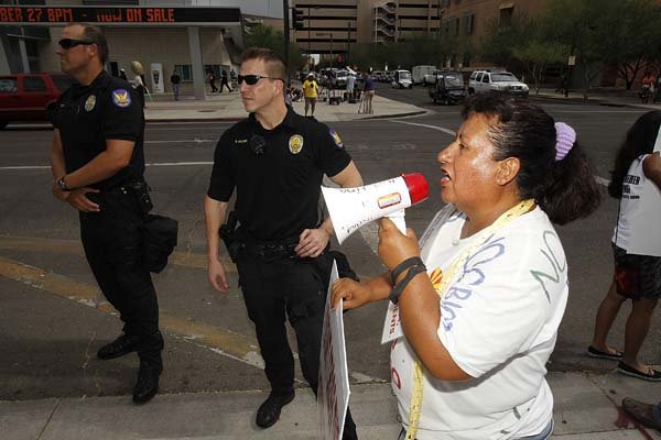 Josephine Nevarez, an opponent of Arizona’s immigration law, uses a bullhorn to make her point as she joins dozens to protest the law Thursday in front of U.S. District Court in Phoenix.