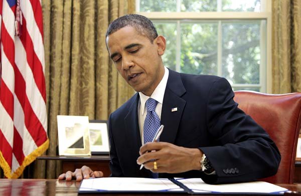 President Barack Obama signs legislation to extend jobless benefits to the long-term unemployed Thursday at the White House.