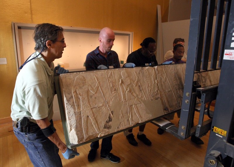 Jean-Louis Lachevre (left), a conservator from the Museum of Fine Arts, Boston, works with Arkansas Arts Center staff members Alex Moomey, Robert Jackson and Quincy Jackson to set down a 678-pound limestone relief from the closed “World of the Pharaohs” exhibition.
