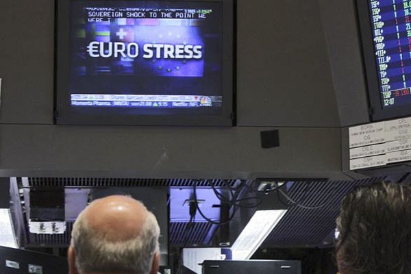 Workers on the floor of the New York Stock Exchange watch news reports Friday showing the results of the “stress tests” on Europe’s banking system.