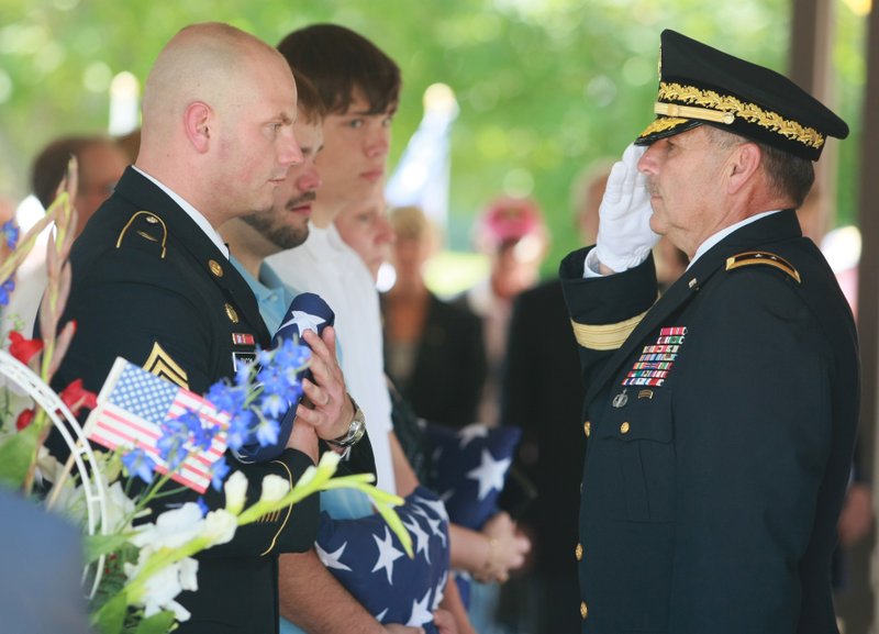 At a memorial service Saturday for Nick Bacon at the Arkansas State Veterans Cemetery, Maj. Gen. William D. Wofford, adjutant general with the Arkansas National Guard, gives a folded U.S. flag to Bacon’s son Army Staff Sgt. James Bacon and other Bacon family members. 	