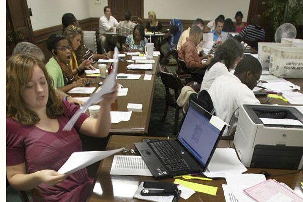 Amber Hood (left) looks over high school transcripts Friday in Little Rock at the state Department of Higher Education as workers process thousands of applications for lottery scholarships.