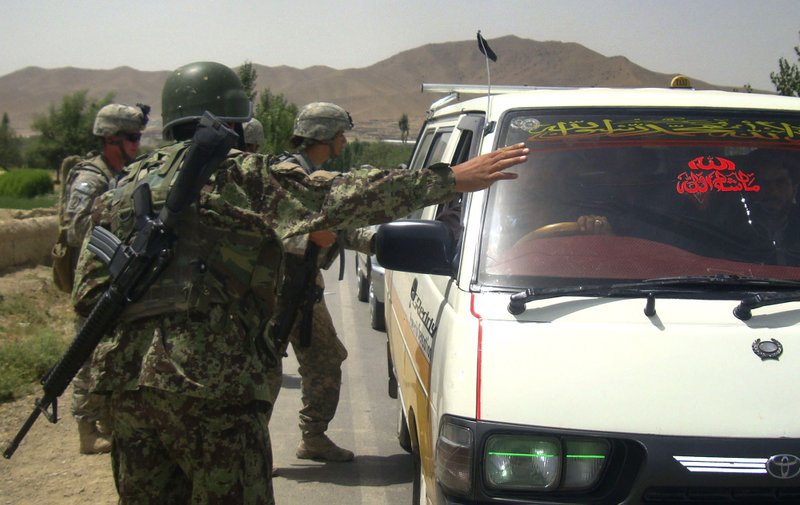 An Afghan soldier stops a mini bus as a U.S. soldier with the NATO-led International Security Assistance Force (ISAF) checks its passengers during a search for the two missing U.S. Navy personnel at a joint check post with Afghan soldiers in Pul-e-alam, Logar province of Afghanistan on Sunday, July 25, 2010. The Taliban have offered to exchange the body of a U.S. Navy sailor they said was killed in an ambush two days ago in exchange for insurgent prisoners, an Afghan official said Sunday. 