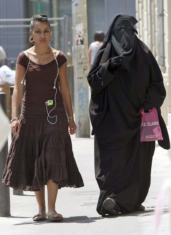 Two women, one a Muslim wearing a veil that exposes only her eyes, walk last summer in downtown Marseille, France. France, Belgium and Spain are considering legislation to ban such veils.