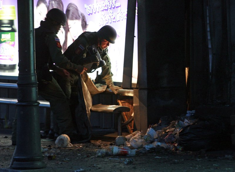 Thai bomb squad members examine the site of a bomb blast near a bus stop in downtown Bangkok, Thailand Sunday, July 25, 2010. The bomb blast wounded nine people Sunday shortly after polls closed in a parliamentary election that pitted a government candidate against a jailed leader of recent mass protests in the Thai capital. 