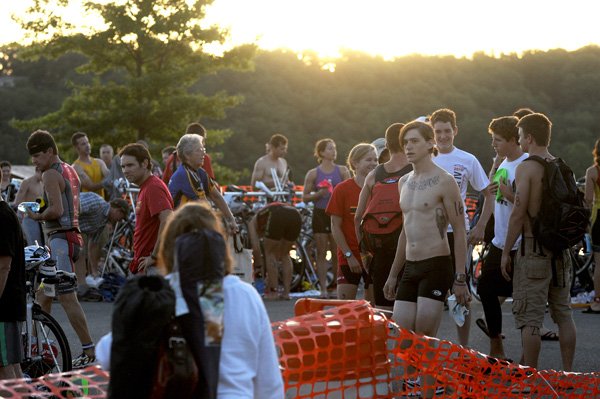 Competitors gather in the transition area shortly after sunrise waiting to begin the Shark Fest IV Triathlon at Horseshoe Bend Park on Sunday at Beaver Lake. The winner of the Olympic Distance men’s division, Maxwell Sawyer, No. 16, stands shirtless at right.