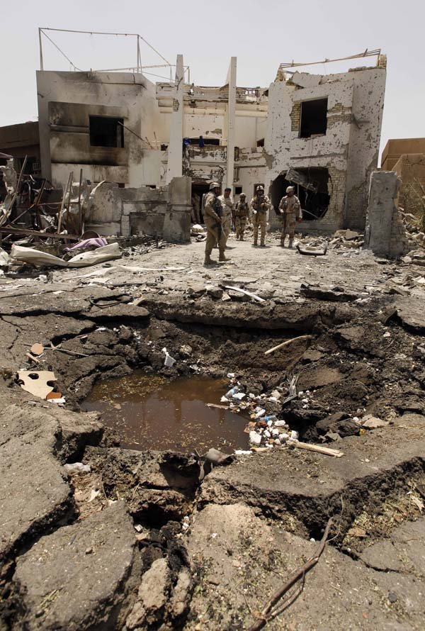Iraqi soldiers stand near a crater outside the Al-Arabiya television station Monday in Baghdad after a suicide bomber detonated a minibus that apparently was waved through two checkpoints.