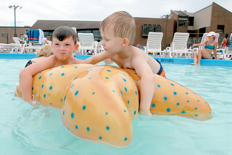 Grant Moses (L) tries to grab onto a floating starfish while Hayden Phillips also enjoys floating at Maumelle's Dowell Naylor Aquatic Center on Friday. 