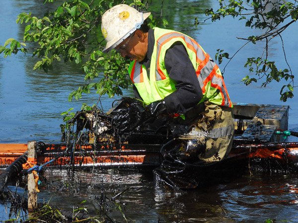 A worker lifts oil-covered debris from the Kalamazoo River in Battle Creek, Mich. Tuesday.