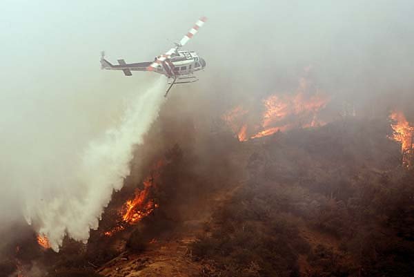  A fire helicopter drops water on the fire at Old West Ranch were residents were evacuated due to a wildfire about 10 miles southeast of the Mojave Desert town of Tehachapi, Calif.