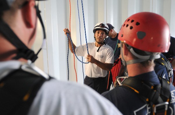 Rick Portilloz of Sand Springs, Okla., talks Wednesday with Rogers firefighters while training for a rope rescue inside a Rogers water tower. Portilloz said rope rescues are rare but when needed are high risk and need to be performed by well-trained personnel.