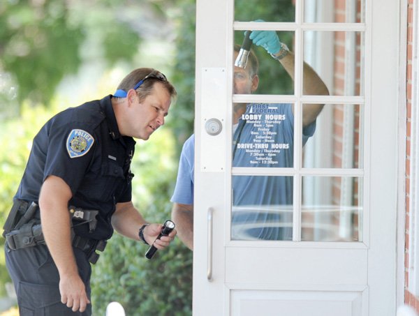 FILE — Sgt. Shannon Gabbard, left, and John Brooks, crime scene investigator, work on July 29, 2010 to collect fingerprints from the front door of First Federal Bank at 3460 N. College Ave. after it was robbed in Fayetteville. Police have linked the robber to nearly a dozen other bank robberies in Louisana, Oklahoma and New Mexico.