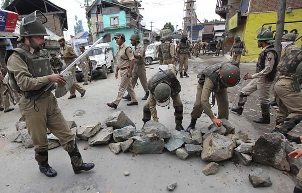 Police remove rocks used by Kashmiri Muslim protesters to block a road Friday in Srinagar, India.