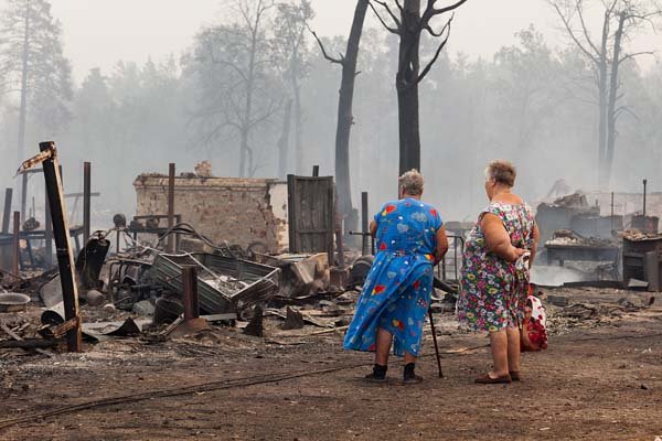 Women survey the damage Friday after a forest fire raged through the village of Mokhovoe, Russia.