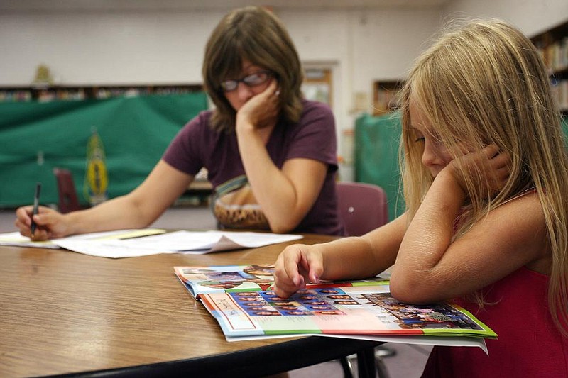 Arkansas Democrat-GazetteWILLIAM MOOREGracie Hammontree, 6, reads a magazine while her mom, Alison Hammontree of Fayetteville, fills out registration paperwork Tuesday, August 3, 2010 at Leverett Elementary in Fayetteville.  Gracie will enter the first grade at Leverett when the school year for Fayetteville Public Schools starts August 19.