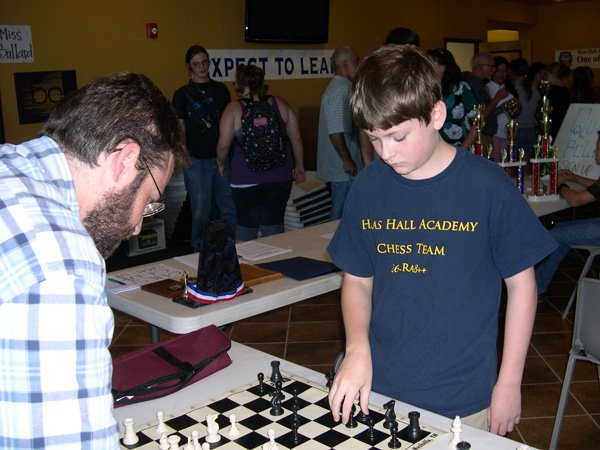Alex Wolf, 14, right, challenges his dad, Patrick Wolf, a University of Arkansas professor in education reform, to a game of chess Thursday during an open house at Haas Hall Academy in Fayetteville. The younger Wolf participated in two national chess tournaments this summer. He is one of 294 students who plan to attend Haas Hall when the public charter school opens Wednesday.
