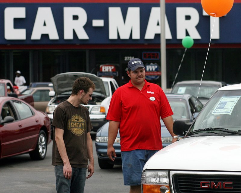 Guy Eaton of Prairie Grove talks with detailer Chris Walton while shopping for cars Saturday at America’s Car-Mart in Fayetteville.