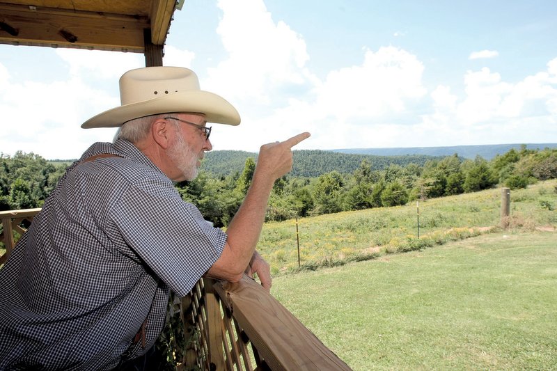 Charles Baker points to the area visible from his back porch, but not on his Star Mountain property, where windmill construction is planned. Baker opposes the project.