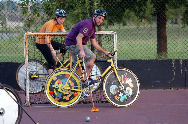 Dave O'Brien (right) defends the goal as Aly Signorelli rounds the back of the goal during a game of bike polo. Little Rock Bike Polo (LRBP) plays several times a week at MacArthur Park on the old roller-hockey court.