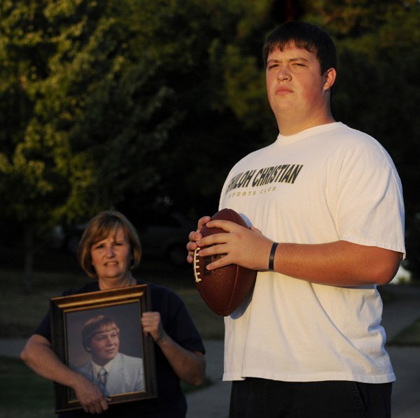 Shiloh Christian offensive lineman Travis Bodenstein stands with his mother, Pam, as she holds a photo of his father, Kevin, at their home on Friday in Springdale.