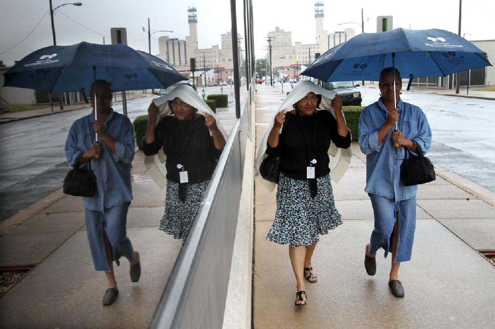 Arkansas Democrat-GazetteBENJAMIN KRAIN --9210--Margie Bates, center and her friend R. Washington walk down 7th Street in the rain to return to work after a lunch break.