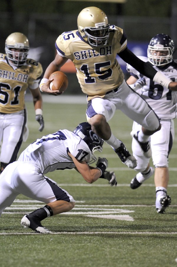 Shiloh Christian quarterback Kiehl Frazier leaps over Greenwood junior defensive back Hayden Smith in the first quarter Friday in Champions Stadium in Springdale. Visit http://photos.nwaonline.net/ to see more photos from the game.