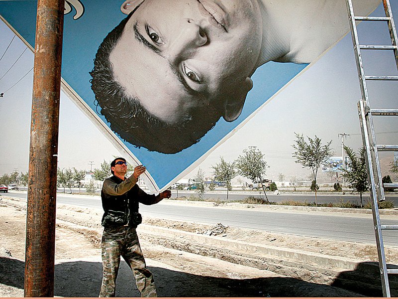 A worker dismantles a political poster Monday in Kabul, Afghanistan, two days after the country’s parliamentary election.