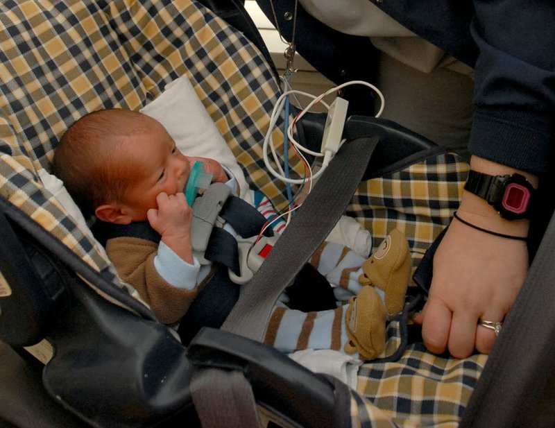 Mary Frances Dooley (foreground), a RN and a child passenger safety technician at UAMS place two-day old premature infant Brenden Johnson in a car seat. Premature babies need to be capable of sitting up without losing oxygen or heart rate. 