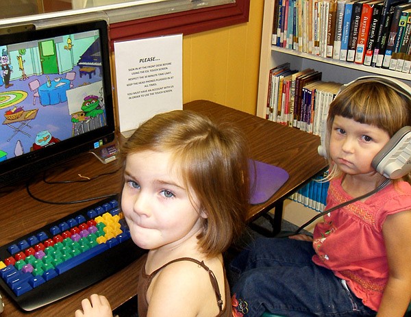 Gracie Robinson and Clara Hoggarth try out the new literacy station at the Gravette Public Library. The new equipment is especially fun for children ages 2 to 10, but adults will find it helpful in learning new languages including Spanish and German.