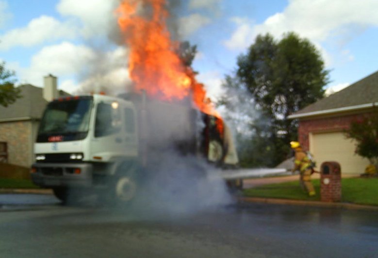 Firefighters douse a Little Rock street sweeper with water after it became engulfed in flames Wednesday morning in a West Little Rock neighborhood.