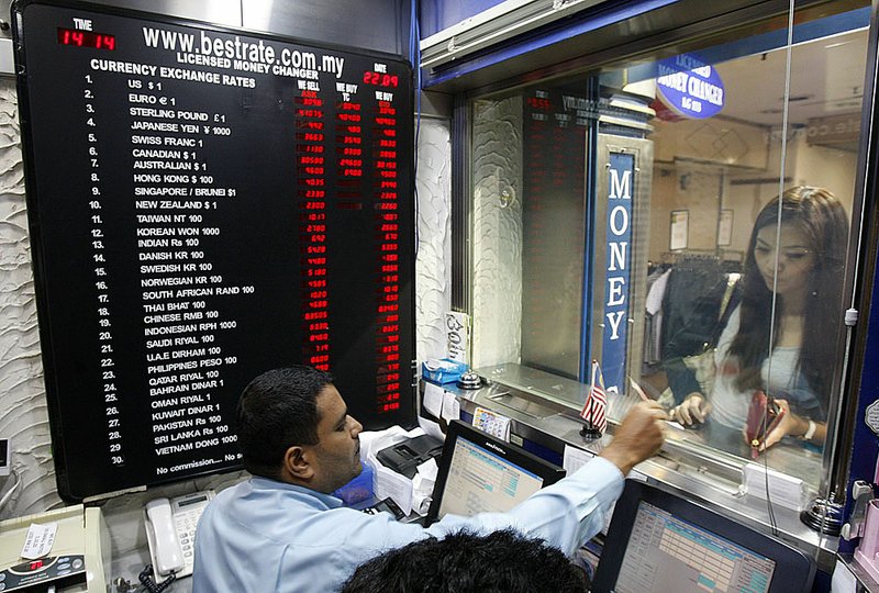 A customer exchanges money at a currency-exchange counter Wednesday in Kuala Lumpur, Malaysia.