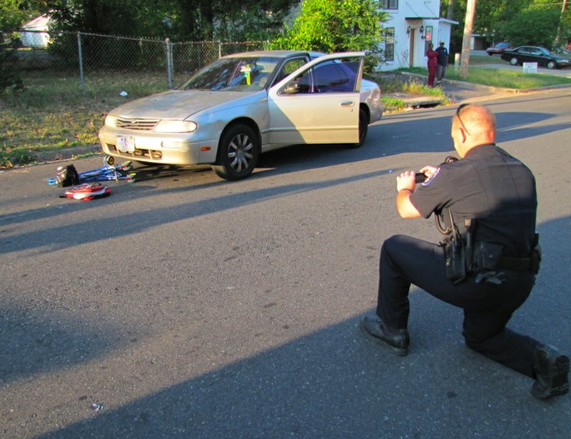 A North Little Rock police officer photographs the scene where three children and their mother were hit by a car Thursday morning.