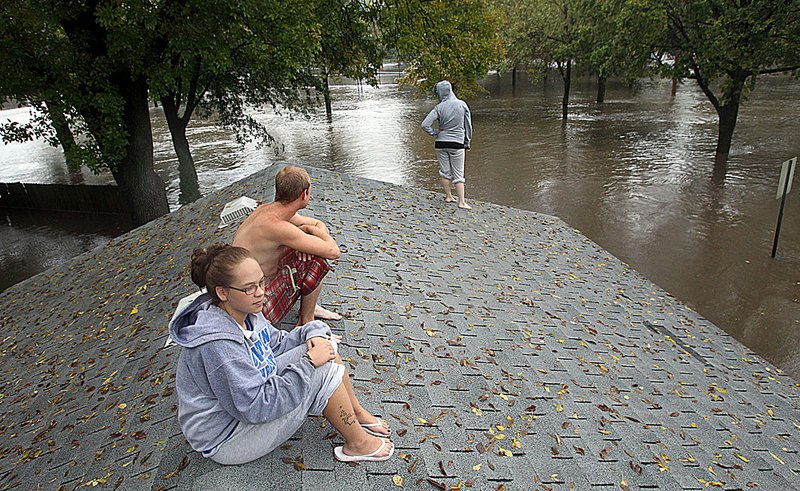 From the roof of her family’s garage, Carrie Larson watches floodwaters rise around her house Thursday in Owatonna, Minn.
