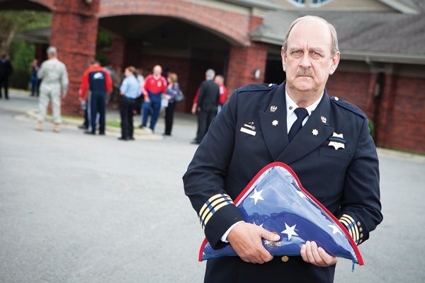Patrick Moore of Conway, president of the National Association of Emergency Medical Technicians, stands in front of The Church Alive before a memorial service earlier this month. He holds one of the U.S. flags to present to families of three people killed in an Air Evac helicopter crash on Aug. 31. 