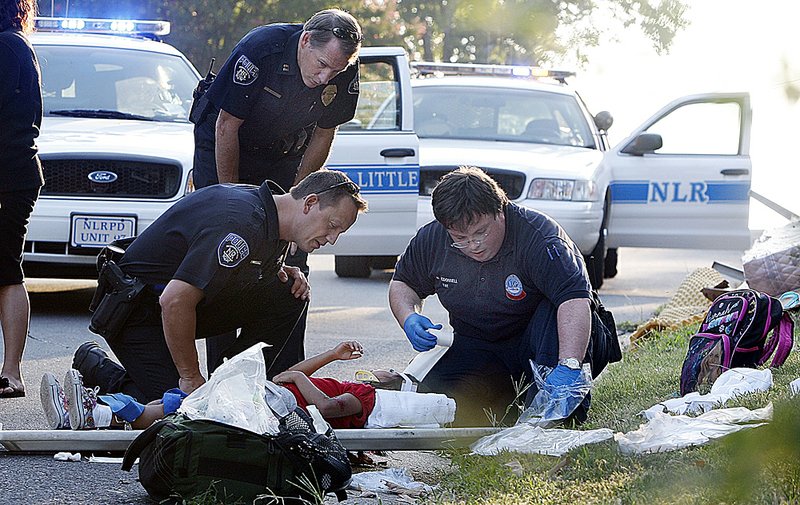 North Little Rock police and MEMS personnel attend to one of three children struck by a car Thursday morning at 45th Street and Pike Avenue in North Little Rock. The children and their mother were hit by the car as they crossed 45th Street. The driver of the car told police she did not see the pedestrians because the sun was in her eyes. All four victims were transported to hospitals with non-life-threatening injuries. 