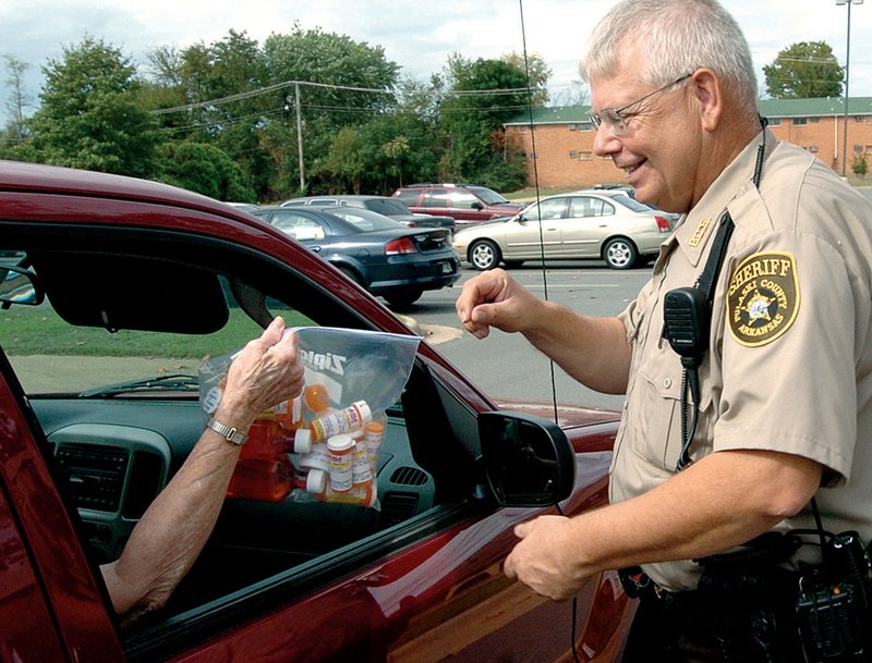 Deputy David Garren takes a bag of unwanted prescription medicines from a resident Saturday at a drop-off site outside the Pulaski County sheriff’s office. 