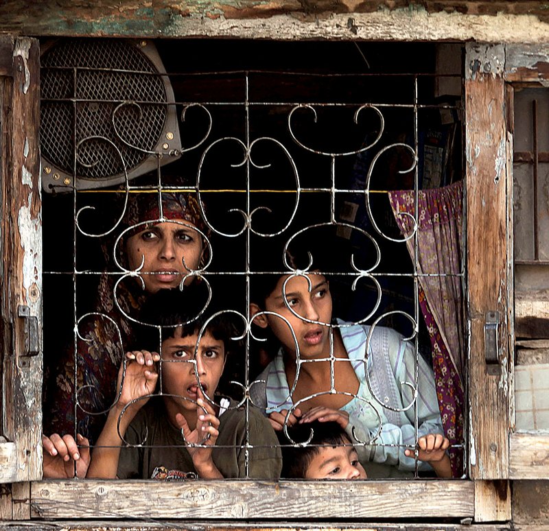 Members of a Kashmiri family in Srinagar, India, peer out from their home Saturday after a clash outside between government soldiers and protesters. The Indian government called Saturday for a policy shift on Kashmir. 