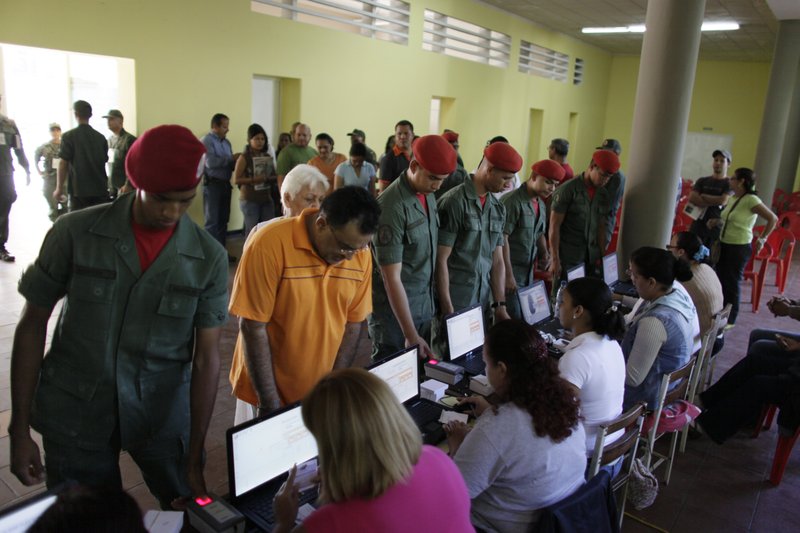 Soldiers have their finger prints registered in a machine before voting at a polling station during congressional elections in Caracas, Venezuela, Sunday, Sept. 26, 2010. 