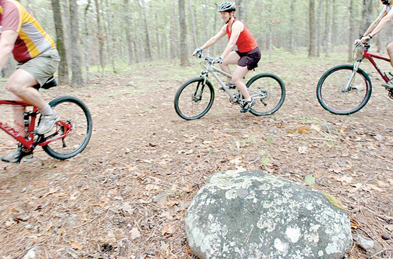 A bench will be placed beside the Rabbit Ridge Trail across from this large stone, so parents have something to look at while their children ride the easy course at Pinnacle Mountain State Park. Daron Harris (from left), Lisa Mullis and Joe Jacobs built the trail expressly for beginners.