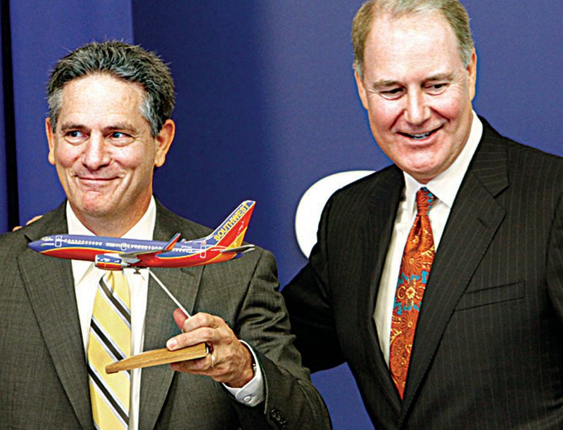 AirTran Airways Chairman, President and CEO Bob Fornaro (left) smiles after being handed at scale model of a Southwest Airlines passenger jet by Southwest Airlines Chairman, President and CEO Gary C. Kelly on Tuesday at Southwest Airlines headquarters in Dallas.