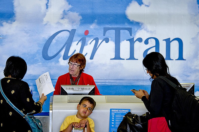 AirTran passengers check in with an airline representative Monday at Hartsfield-Jackson International Airport in Atlanta. Southwest Airlines has announced plans to purchase AirTran.