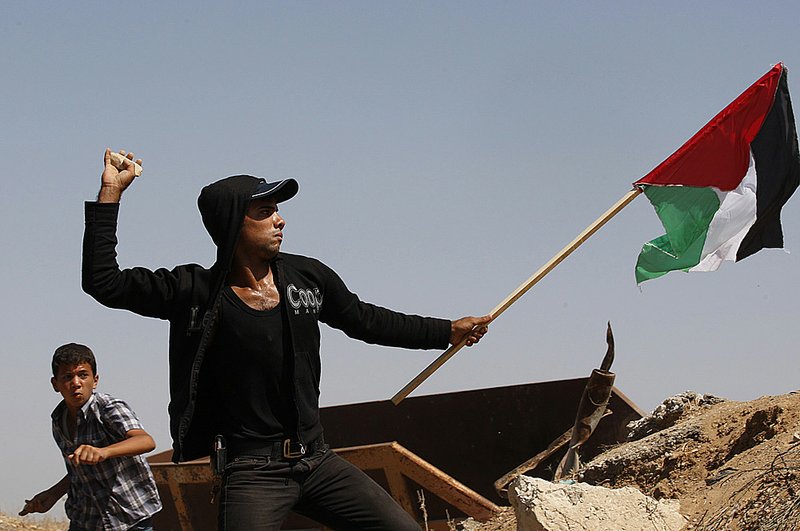 A Palestinian throws stones at Israeli soldiers during a demonstration Wednesday against the Gaza blockade.