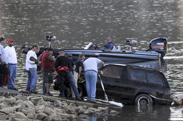 Police and rescue officials look at the interior of a GMC Jimmy belonging to Kelly Lockhart pulled from Beaver Lake on Friday near the U.S. 412 bridge east of Springdale. A body was found inside the vehicle. Lockhart has been missing since 2008. Police have indentified two suspects and consider her death a homicide.
