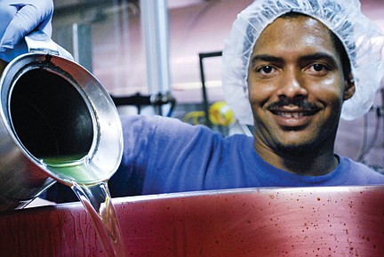 Employee T.J. Smith pours the secret flavoring ingredient into the mixing vat. A 5-gallon pail of grape concentrate makes enough Grapette to fill 30 swimming pools. 